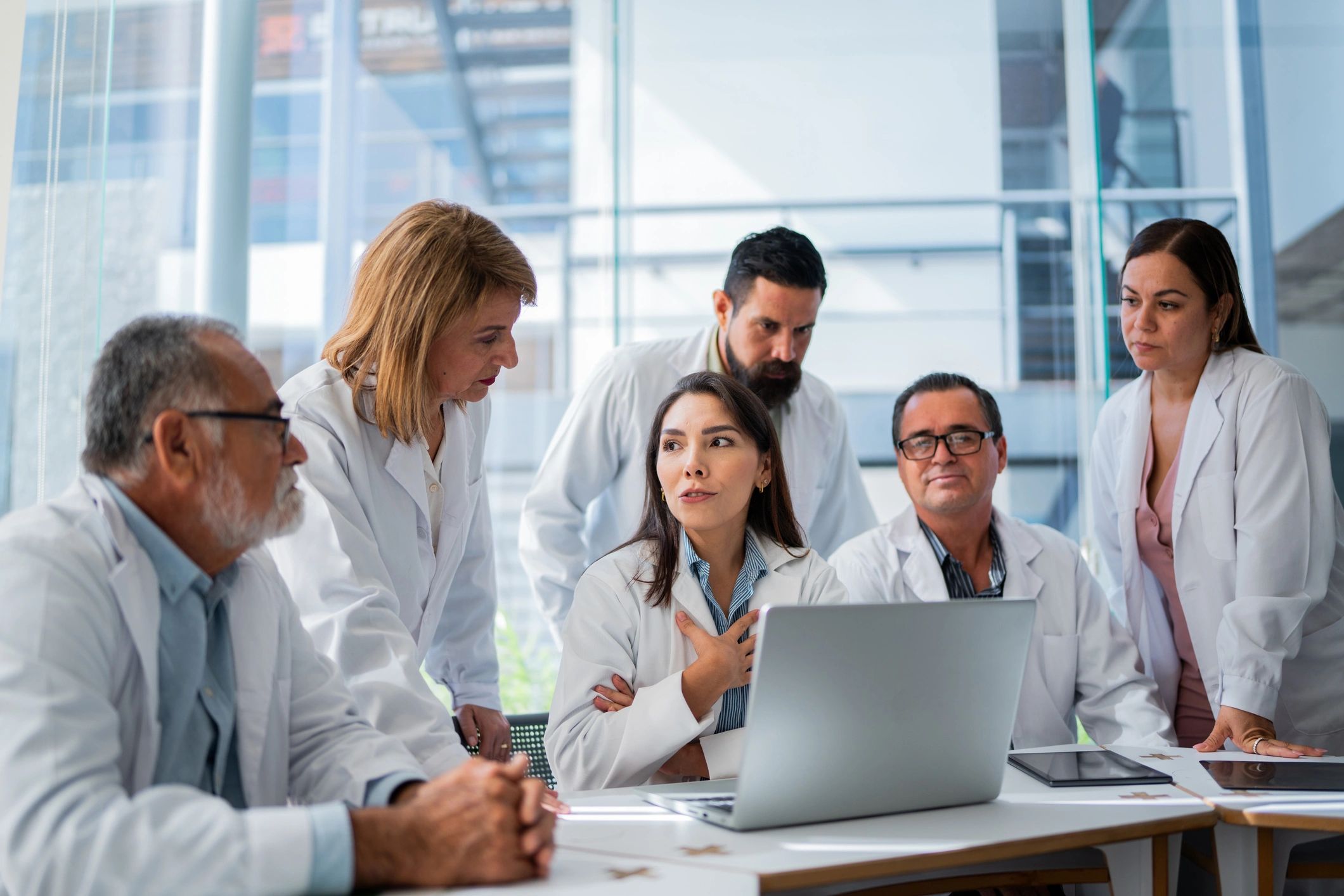 Doctors collaborating with a laptop during a hospital meeting